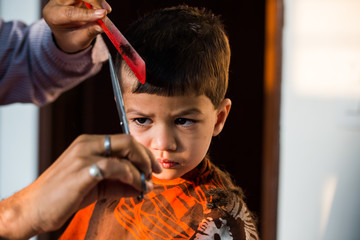 two year old kid having a haircut  with wet eyes after crying early morning with golden light...