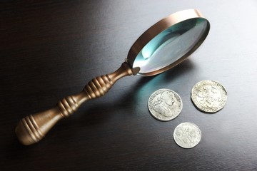 Vintage Magnifying Glass And Old Silver Coins On Black Table