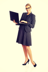 Businesswoman standing and holding a laptop