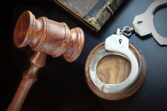 Judges Gavel, Handcuffs And Old Book On The Black Table