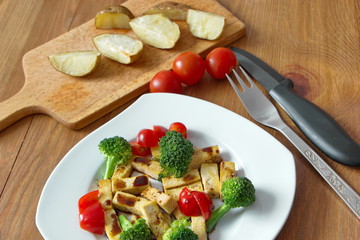 pieces of roasted tofu with broccoli, tomatoes and soy sauce
