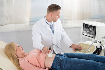 Doctor Moving Ultrasound Transducer On Pregnant Woman's Belly