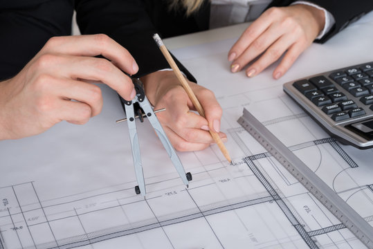 Architects Working On Blueprint At Desk In Office