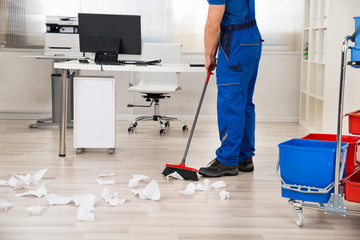 Janitor Sweeping Floor With Broom In Office