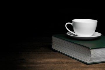 Empty Tea Cup On The Green Old Book In Dark