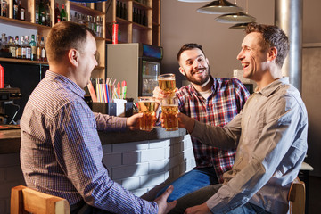 Fototapeta na wymiar Happy friends drinking beer at counter in pub