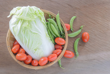 Tomato,Chinese cabbage,Sweet peas,Bamboo basket on wooden floor.