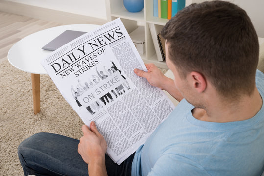 Man Reading News On Newspaper At Home