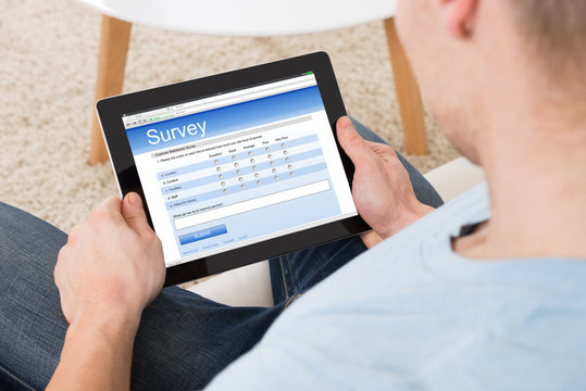 Man Filling Survey Form Online On Digital Tablet At Home