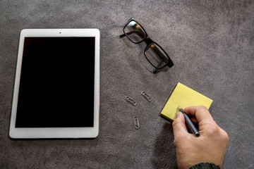 Homme écrivant une note sur un post-it au bureau