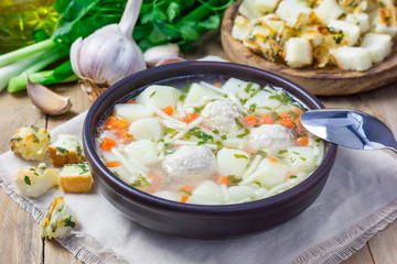 Homemade soup with meatballs and vegetables, served with cheese-garlic-parsley croutons