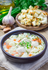 Homemade soup with meatballs and vegetables, served with cheese-garlic-parsley croutons
