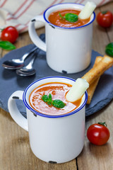 Homemade tomato basil soup in the mug, served with mozzarella cheese stick and croutons