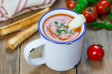 Homemade tomato basil soup in the mug, served with mozzarella cheese stick and croutons