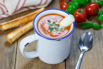 Homemade tomato basil soup in the mug, served with mozzarella cheese stick and croutons