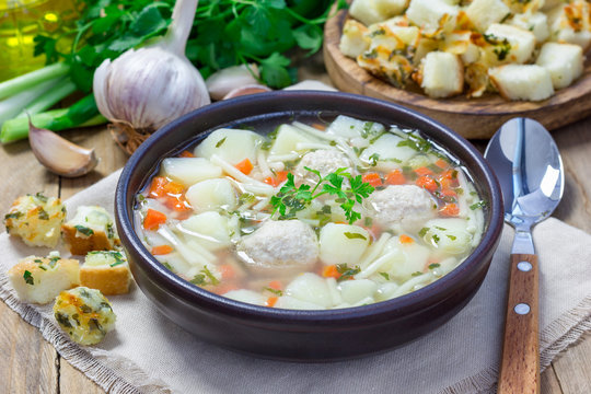 Homemade soup with meatballs and vegetables, served with cheese-garlic-parsley croutons
