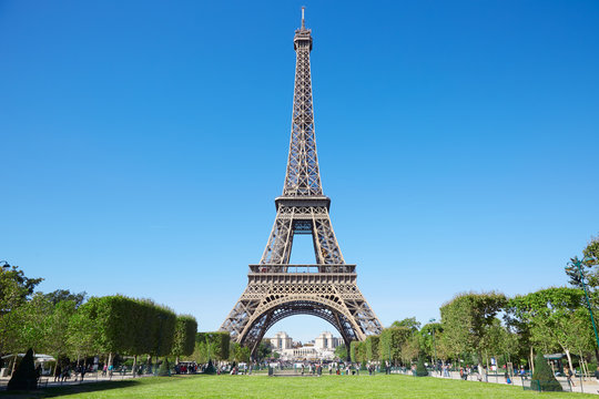 Eiffel tower, sunny summer day with blue sky and green Field of Mars