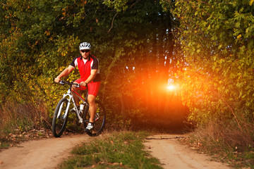 Man is cycling in autumn forest