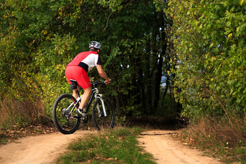 Man is cycling in autumn forest