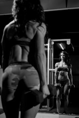 Fototapeta na wymiar Black and white image of Woman working out in a gym with weights