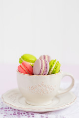 Colorful tiny macaroons in vintage coffee cup