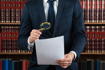 Lawyer Examining Legal Documents With Magnifying Glass