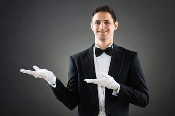 Confident Waiter Presenting Invisible Product - obrazy, fototapety, plakaty
