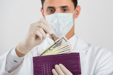 Male Surgeon Removing Banknote From Wallet