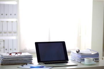 Laptop with stack of folders on table on white background