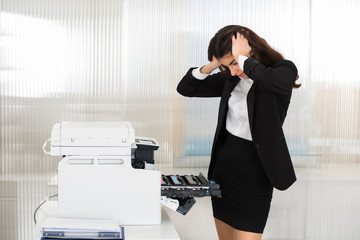 Irritated Businesswoman Looking At Printer Machine At Office