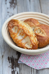 Two fresh backed buns - with cheese and salt in wooden bowl on wooden table. Fresh and hot, perfect for your meal - your lunch or breakfast. Natural light, selective focus.