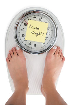 Woman Standing On Weight Scale With Loose Weight Note