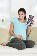 Obraz premium Happy Pregnant Woman Holding Ultrasound Scan On Sofa