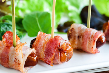 Macro close up of dates with bacon skewers.