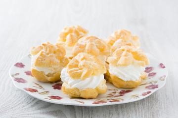 Fresh profiteroles with cream on plate
