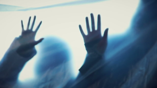 Human silhouettes behind transparent film stretching hands, scary nightmare