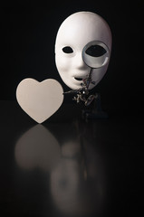 Mask with a monocle and a wooden heart on a black background