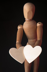 Wooden mannequin with two hearts on a black background
