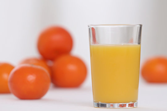 close-up on a full of vitamins glass of orange juice with oranges in the background