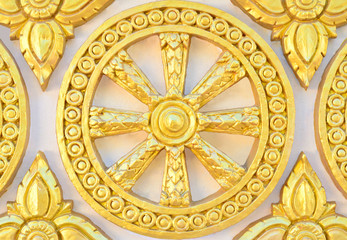 Thai style golden molding wheel of life pattern on temple wall