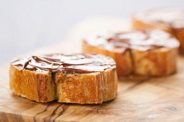 baguette slices with chocolate hazelnut spread on olive board