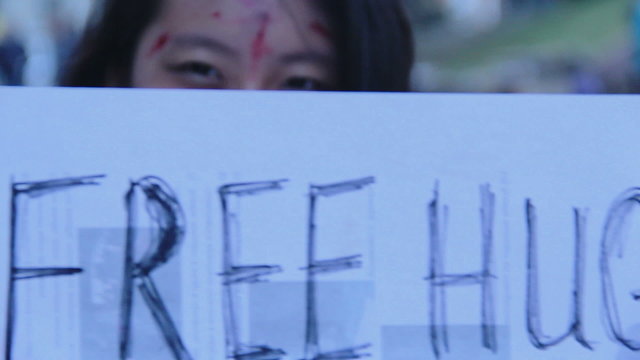 Female teenager enjoying Halloween flash mob, offering free hugs in the street