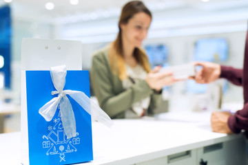 Beautiful female getting present at shop. She is taking present with one hand. Selective focus on present. Shallow depth of field.