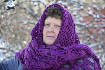  elderly woman in  purple knitted shawl on her head is about Rowan