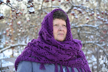  elderly woman in  purple knitted shawl on her head is about Rowan