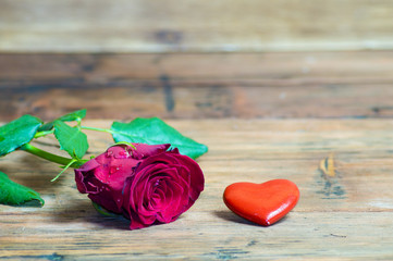 Róża i czerwone serduszko na drewnianym tle
