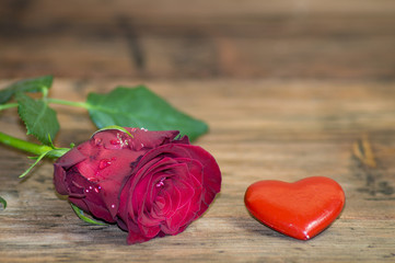 Róża i czerwone serduszko na drewnianym tle