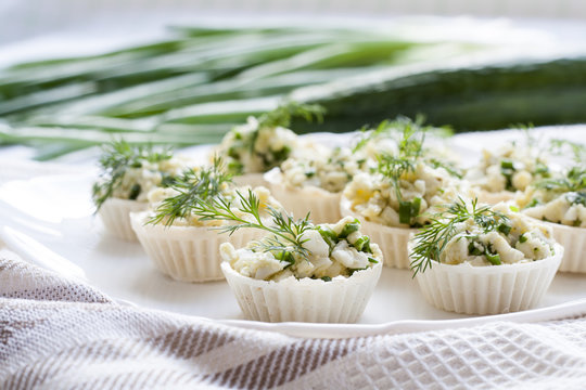 Tartlets with cheese and green onion filling decorated with dill on a dish