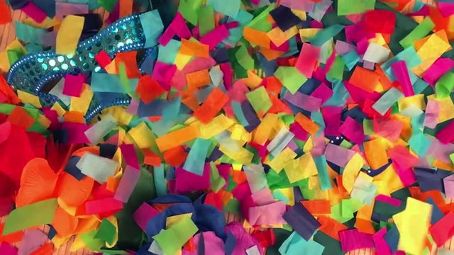 Confetti falling in reverse on Brazil tickets with sparkly carnival mask, colorful flower lei, and Brazilian pennant flag