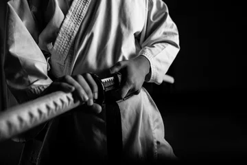 Foto auf Acrylglas Kampfkunst Nahaufnahme eines jungen Kampfsportlers mit Katana in Seiza-Position, schwarz und weiß.